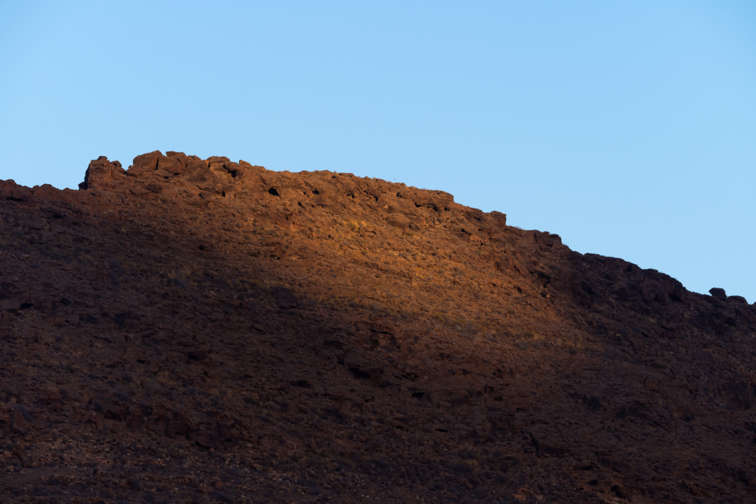 Lone volcanic rock formation under blue sky, Gran Canaria desert