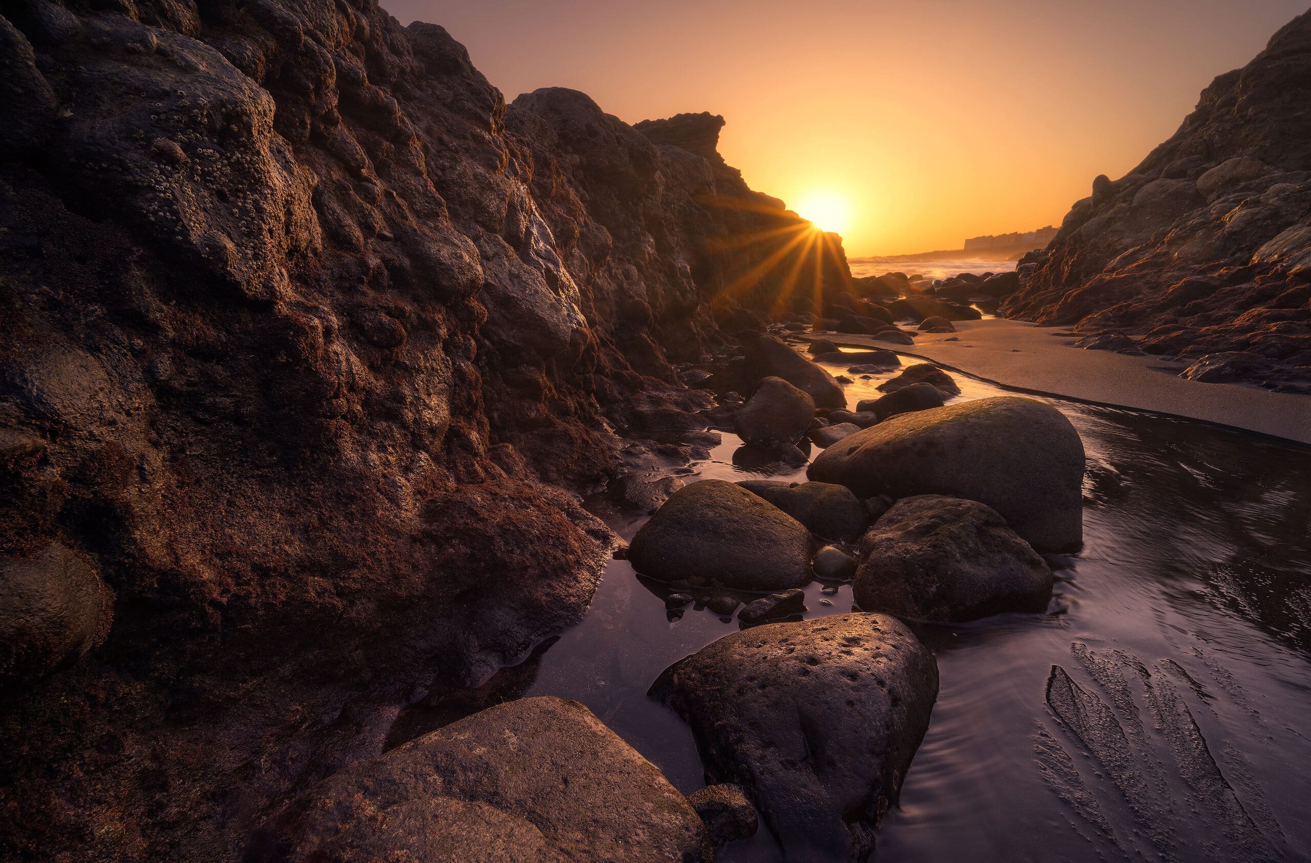 Sunburst through volcanic rock formations at low tide, coastal landscape photography, Gran Canaria