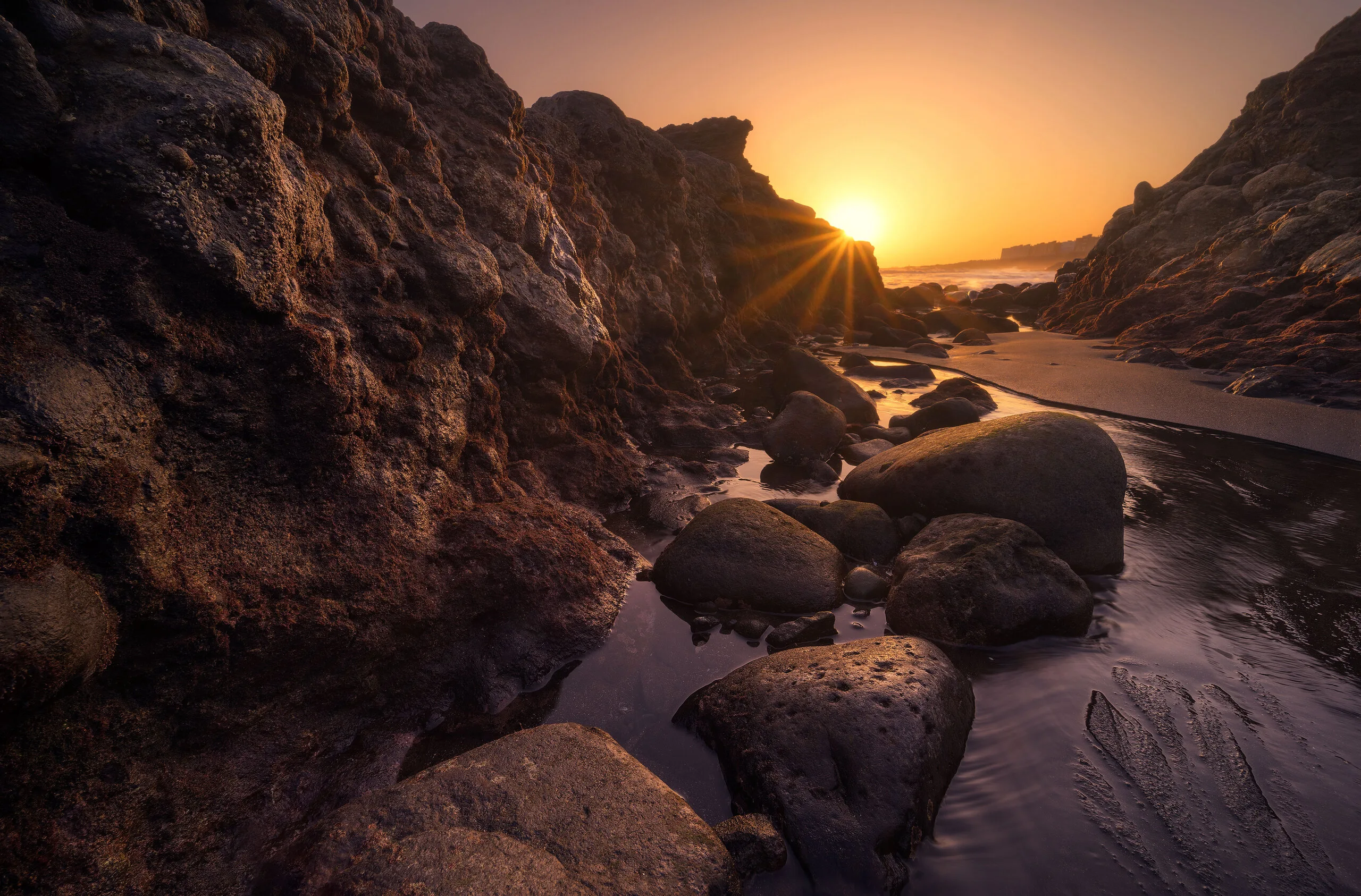 Sunburst through volcanic rock formations at low tide, coastal landscape photography, Gran Canaria